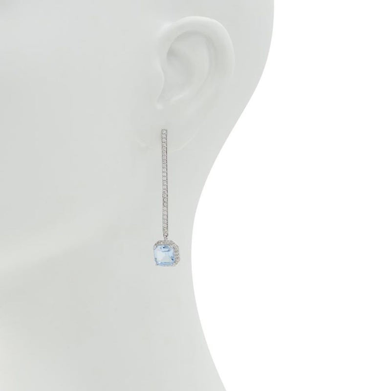 Silver drop earrings with a long pave-set bar and a light blue square crystal on a white mannequin ear
