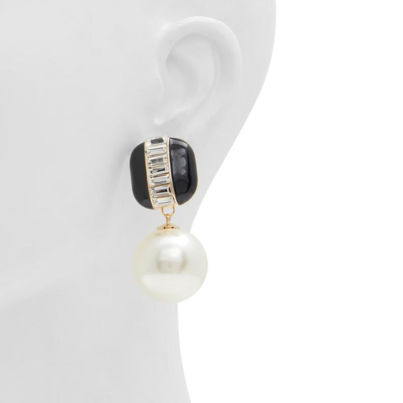 Black and gold statement earrings with crystal baguettes and a hanging white faux pearl on a mannequin ear