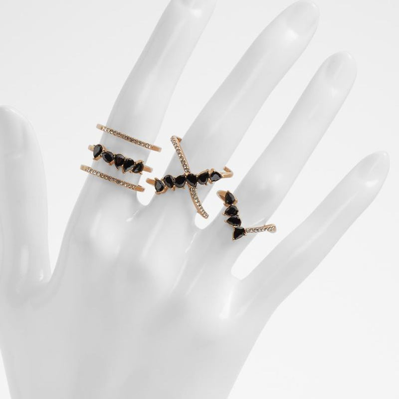 Rose gold metallic rings with black teardrop crystals on a mannequin hand