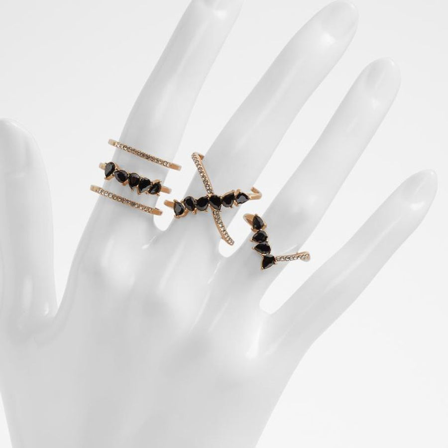 Three gold-tone metal rings adorned with black teardrop stones and small crystals