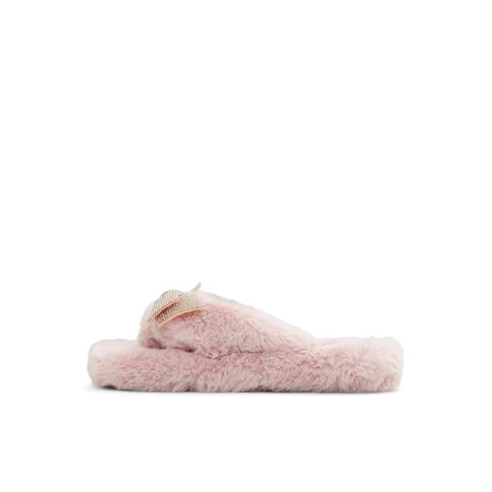 Female model wearing Jil Sander blush pink fluffy shearling thong sandal with an ultra-plush shearling upper, delicate rose gold bow accent, and cushioned shearling platform sole, captured mid-step in a casual lifestyle pose showcasing the sandal's cosy feminine luxury and effortless designer comfort.
