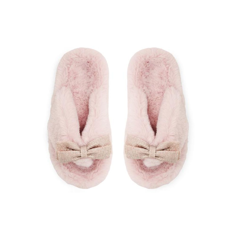 Female model wearing Jil Sander blush pink fluffy shearling thong sandal with an ultra-plush shearling upper, delicate rose gold bow accent, and cushioned shearling platform sole, captured mid-step in a casual lifestyle pose showcasing the sandal's cosy feminine luxury and effortless designer comfort.