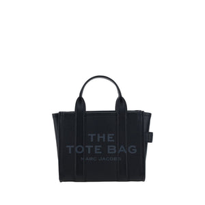 Marc Jacobs black leather handbag featuring "THE TOTE BAG MARC JACOBS" text, dual top handles, and side loops.
