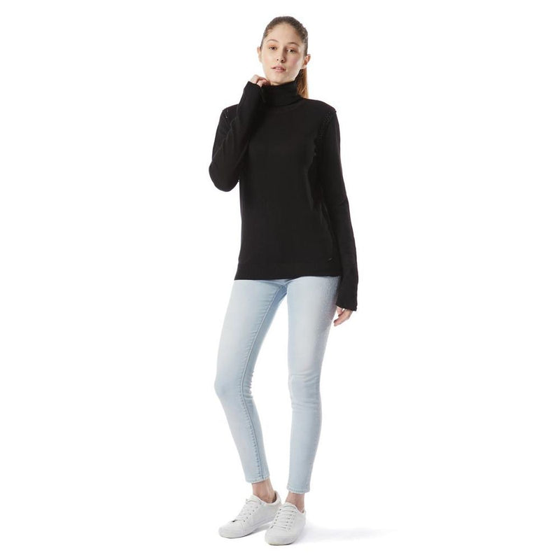 A model wearing a black cotton turtleneck sweater, light wash jeans, and white sneakers