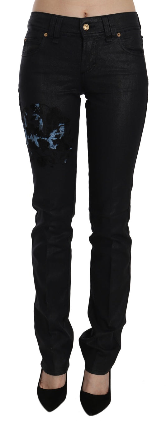 Black mid-waist skinny denim jeans with blue floral embroidery on the right thigh