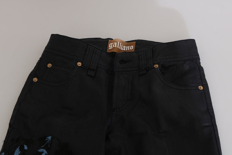 Black denim skinny jeans with blue floral embroidery and a brown Galliano waist patch