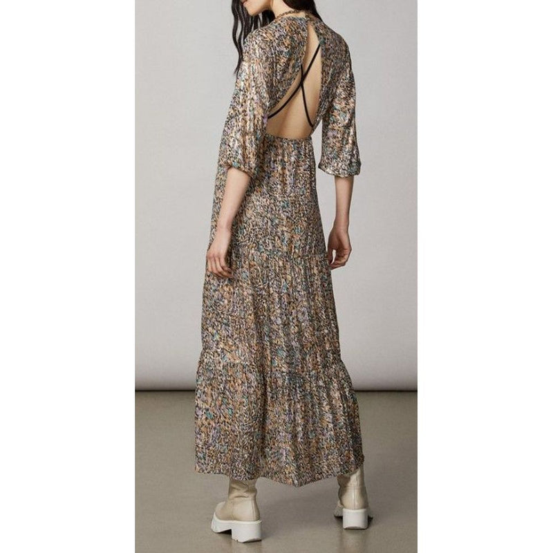 Gold silk casual midi dress with long sleeves, tiered skirt, and open back featuring crisscross black straps