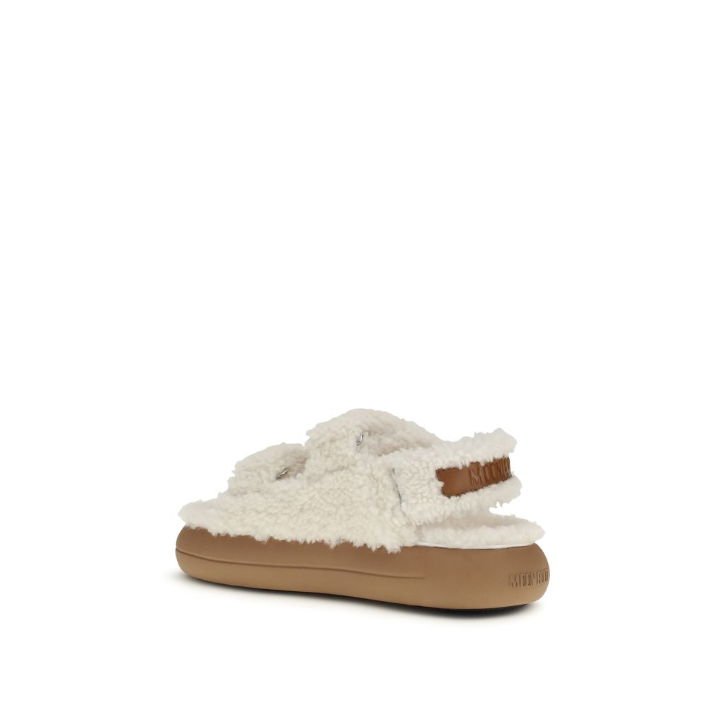 White fuzzy shearling-style Moon Boot slippers with adjustable velcro straps and a flat brown rubber sole.