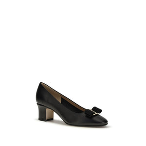 Black calf leather mid-heel pump featuring a signature bow accent and block heel.