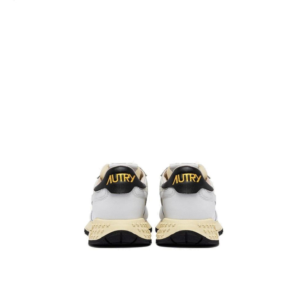 Autry white leather sneakers with black heel tabs, gold logo text, and textured cream midsoles with black rubber outsoles.