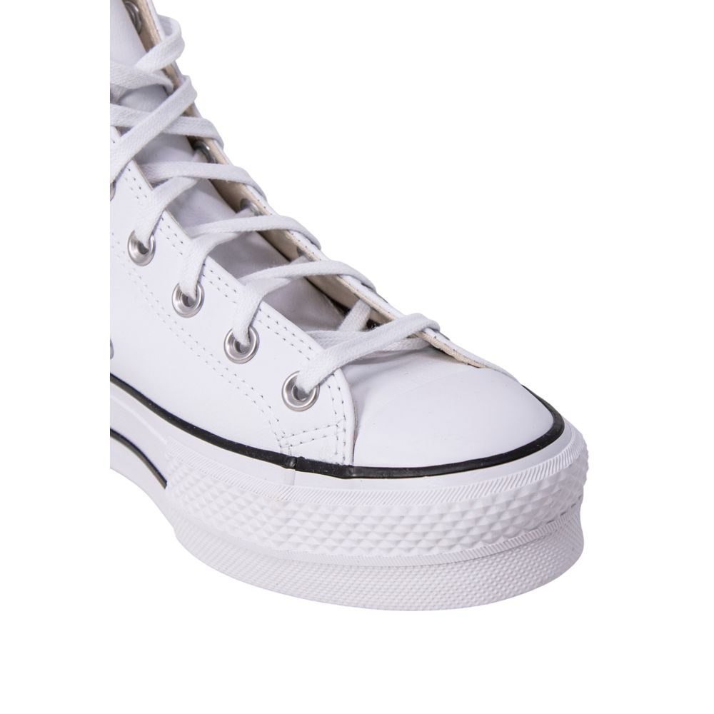 Close-up of a white leather high-top platform sneaker with matching laces, silver eyelets, and a thick rubber sole.