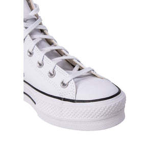 Close-up of a white leather high-top platform sneaker with matching laces, silver eyelets, and a thick rubber sole.