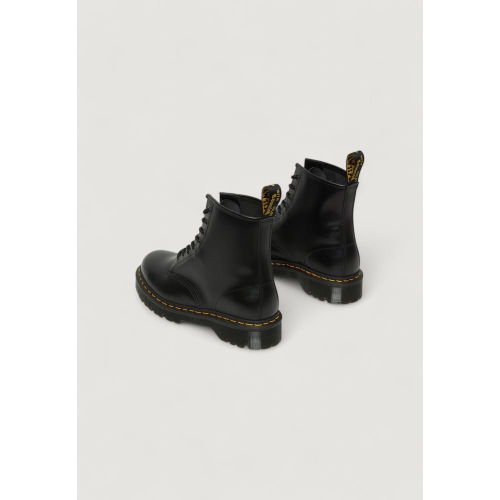 Black leather Dr. Martens lace-up boots with yellow welt stitching and yellow heel loops on a plain background.