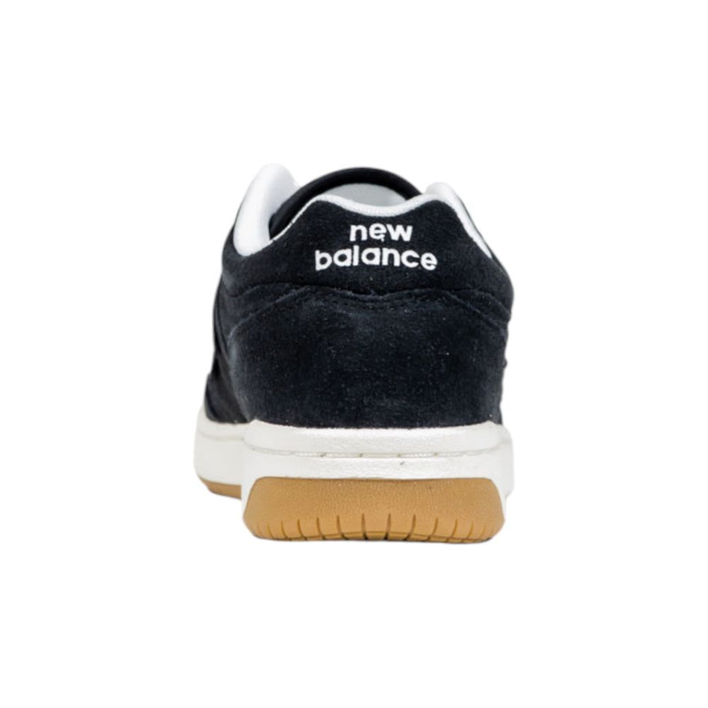 Black suede New Balance sneaker, back view, featuring white logo text, white midsole, and gum rubber outsole.