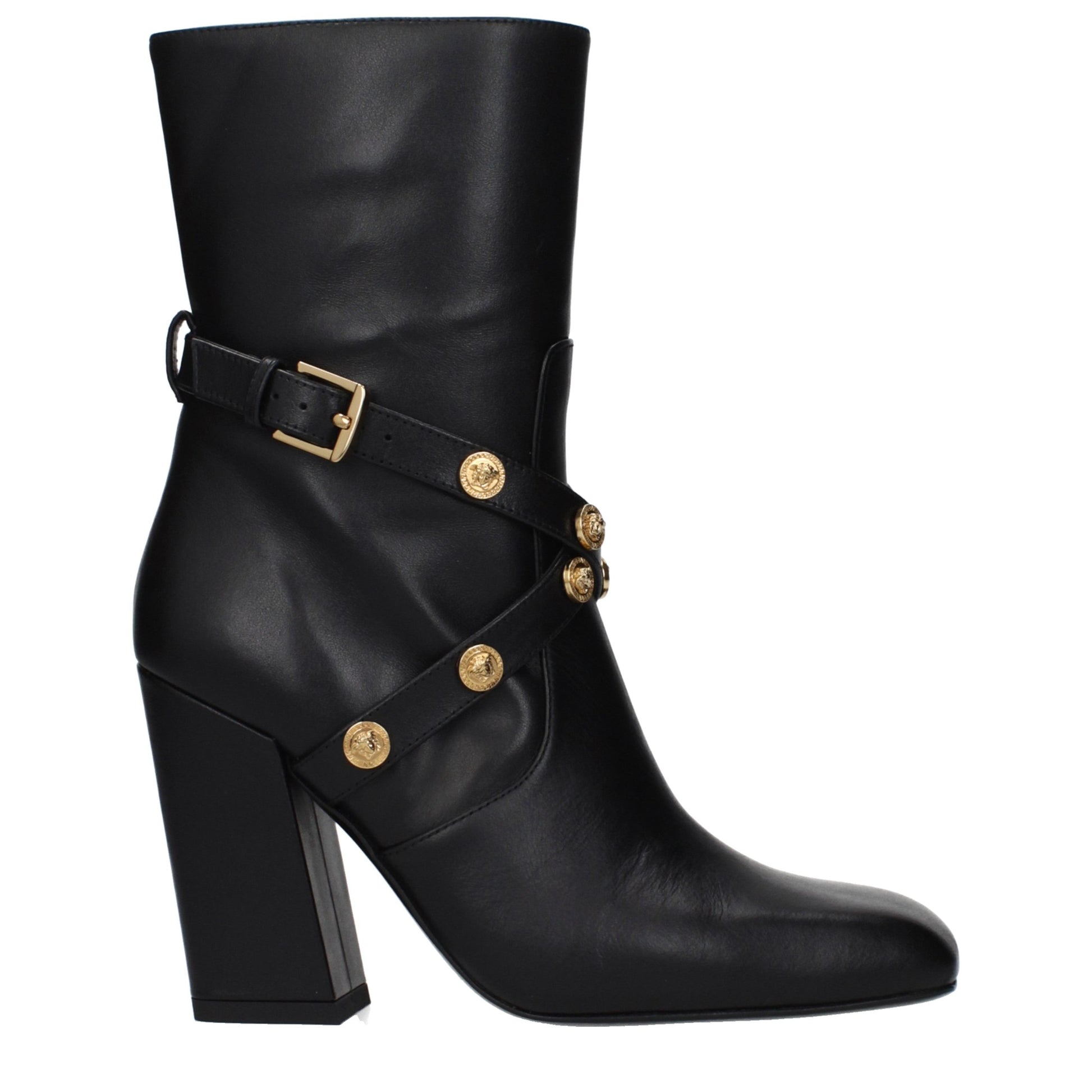 Female model wearing Versace black leather ankle boots with a sleek black leather upper, structured silhouette, and premium luxury finish, captured mid-step in a casual lifestyle pose showcasing the boot's bold profile and iconic Italian craftsmanship.