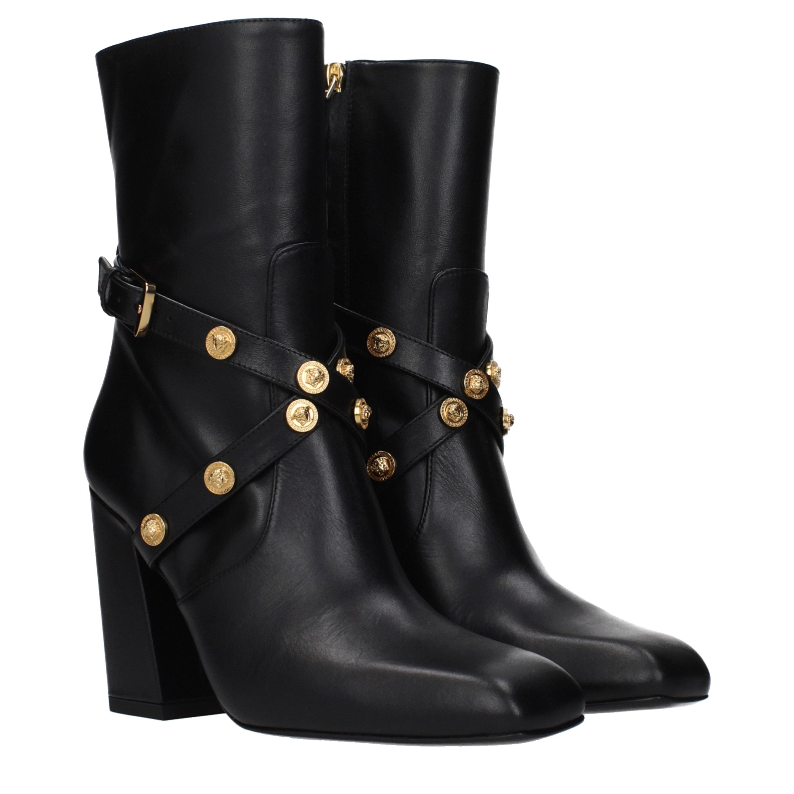 Female model wearing Versace black leather ankle boots with a sleek black leather upper, structured silhouette, and premium luxury finish, captured mid-step in a casual lifestyle pose showcasing the boot's bold profile and iconic Italian craftsmanship.