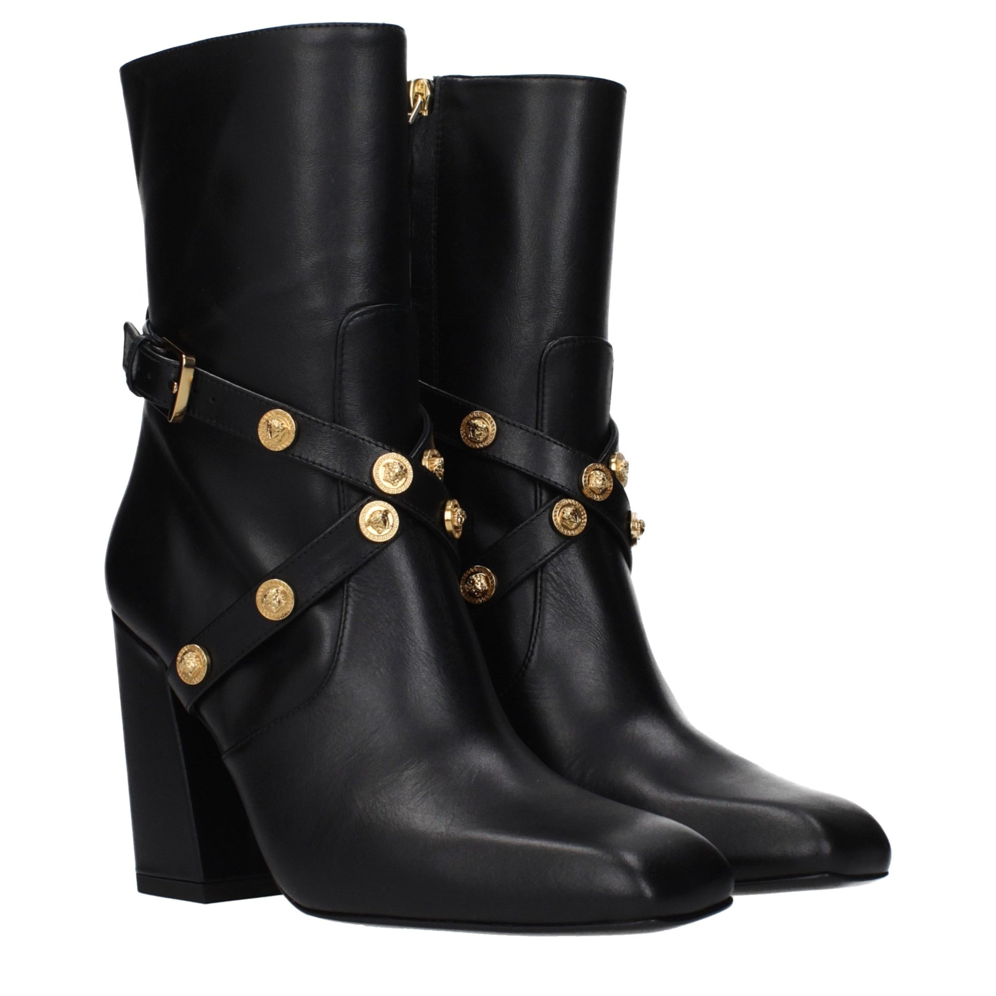 Female model wearing Versace black leather ankle boots with a sleek black leather upper, structured silhouette, and premium luxury finish, captured mid-step in a casual lifestyle pose showcasing the boot's bold profile and iconic Italian craftsmanship.