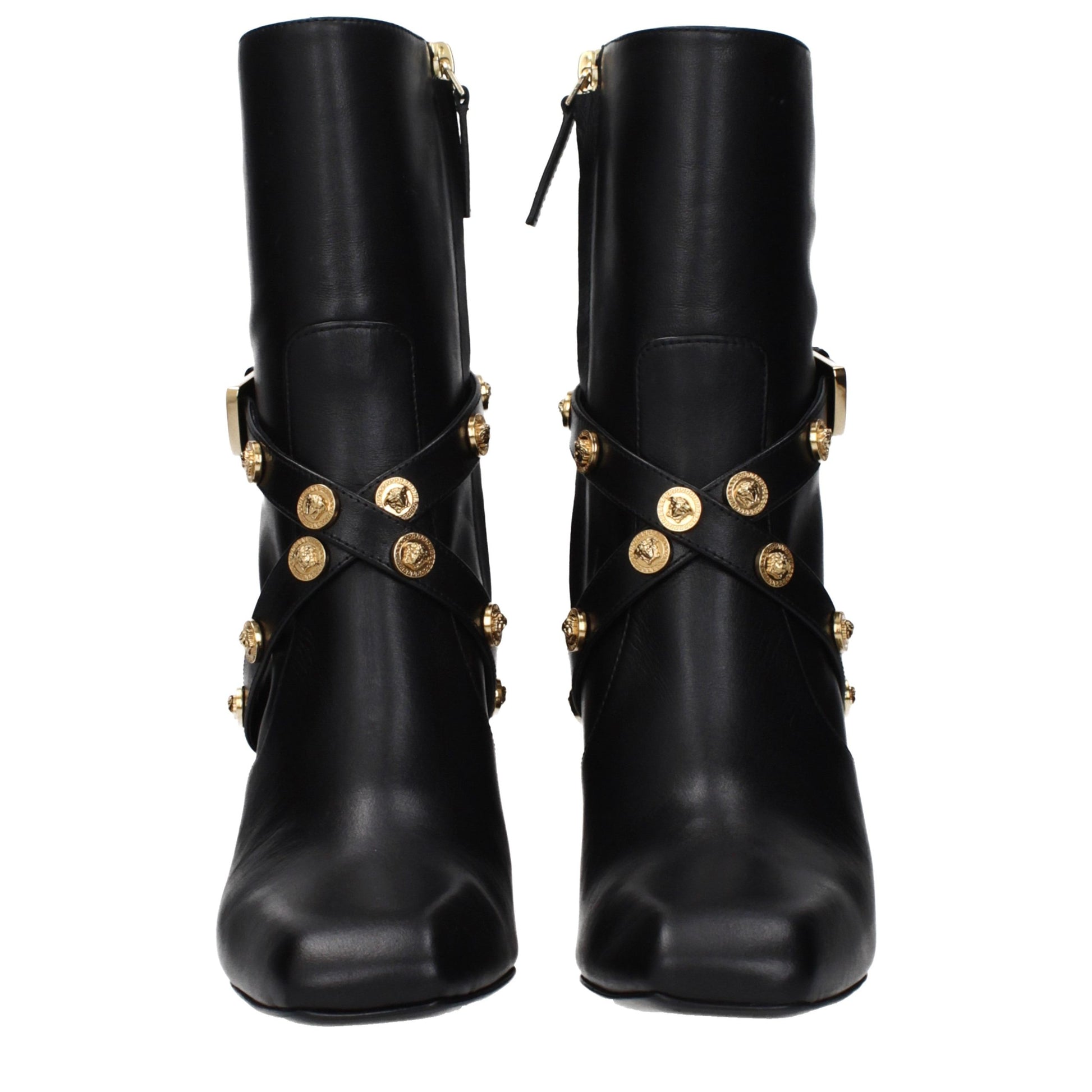 Female model wearing Versace black leather ankle boots with a sleek black leather upper, structured silhouette, and premium luxury finish, captured mid-step in a casual lifestyle pose showcasing the boot's bold profile and iconic Italian craftsmanship.