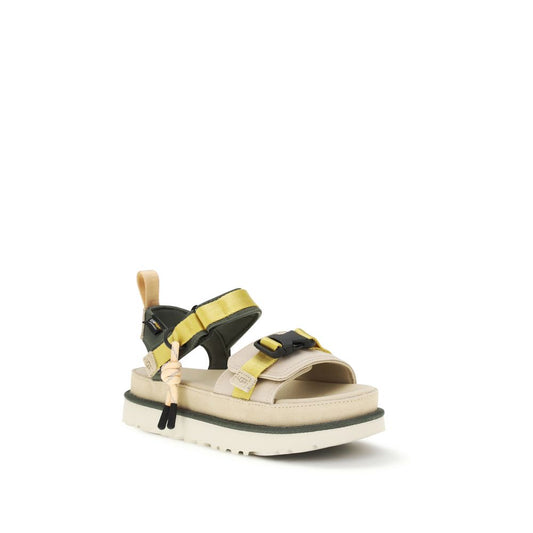 UGG beige and olive green flat sport sandals featuring nylon straps, black buckles, and a thick, textured platform sole.