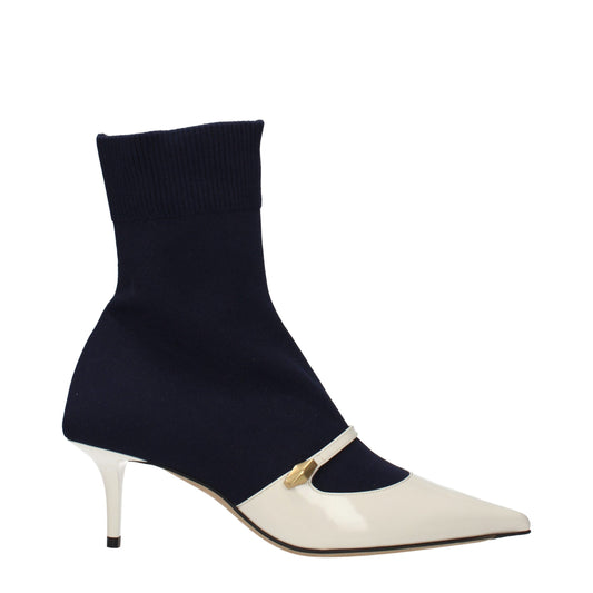 Navy blue stretch-knit sock boot with a pointed-toe white patent leather vamp, gold detail, and kitten heel.