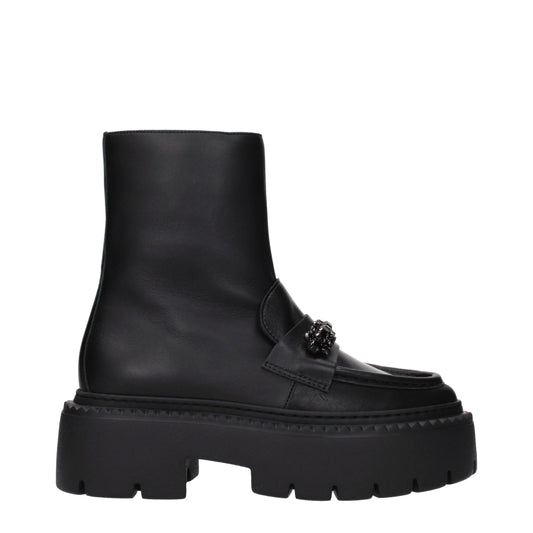 Female model wearing Jimmy Choo black leather ankle boots with a sleek black leather upper, elegant structured silhouette, and premium luxury finish, captured mid-step in a casual lifestyle pose showcasing the boot's refined profile and iconic designer craftsmanship.
