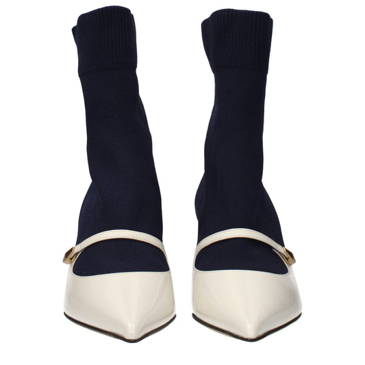 Female model wearing Jimmy Choo blue fabric ankle boots with a rich blue textile upper, refined silhouette, and iconic British luxury craftsmanship, captured mid-step in a casual lifestyle pose showcasing the boot's bold cobalt elegance and effortless designer sophistication.
