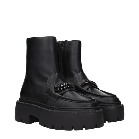 Female model wearing Jimmy Choo black leather ankle boots with a sleek black leather upper, elegant structured silhouette, and premium luxury finish, captured mid-step in a casual lifestyle pose showcasing the boot's refined profile and iconic designer craftsmanship.