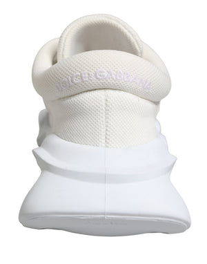 White Dolce & Gabbana slip-on sneakers featuring a textured knit upper and a chunky, sculpted rubber wave sole.