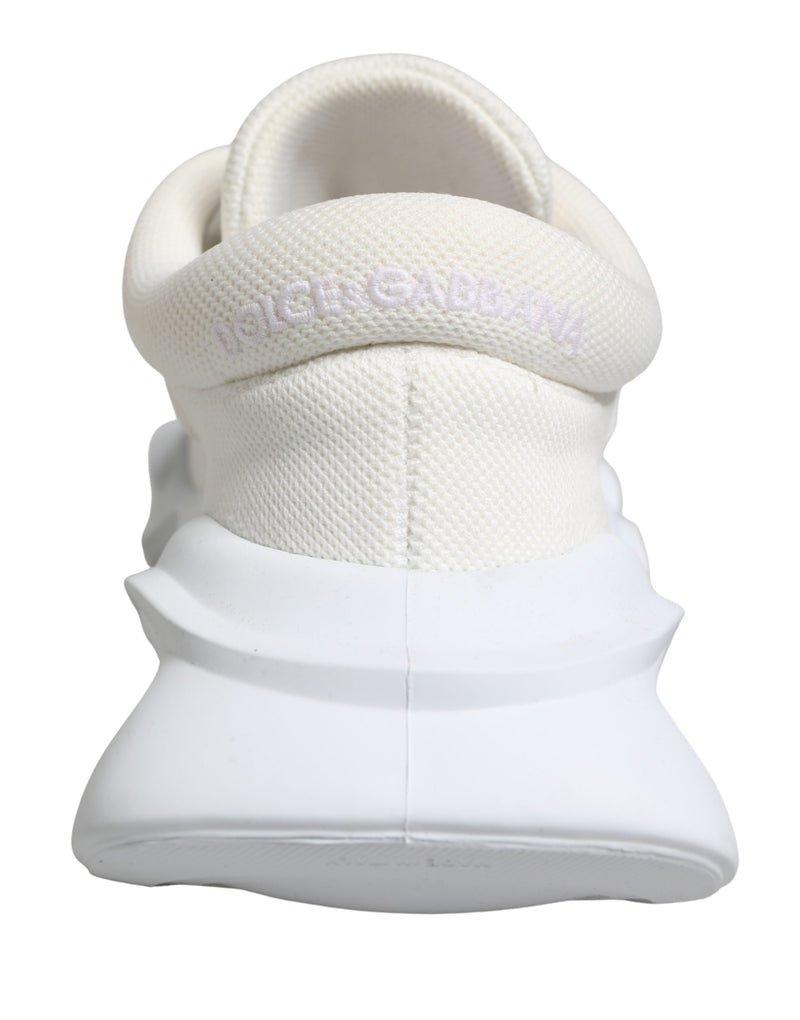 White Dolce & Gabbana slip-on sneakers featuring a textured knit upper and a chunky, sculpted rubber wave sole.