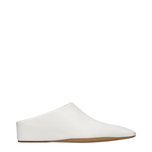 Female model wearing Jil Sander white leather slippers with a clean white leather upper, sleek minimalist silhouette, and refined luxury finish, captured mid-step in a casual lifestyle pose showcasing the slipper's understated elegance and premium German craftsmanship.
