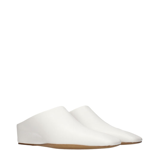 Female model wearing Jil Sander white leather slippers with a clean white leather upper, sleek minimalist silhouette, and refined luxury finish, captured mid-step in a casual lifestyle pose showcasing the slipper's understated elegance and premium German craftsmanship.
