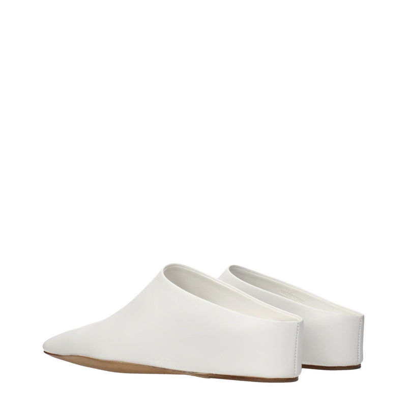 White leather slip-on shoes with pointed toes and flat brown soles