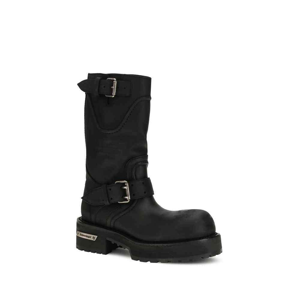 Balenciaga black calf leather biker boot with dual buckled straps, a thick lug sole, and a metallic brand logo detail.