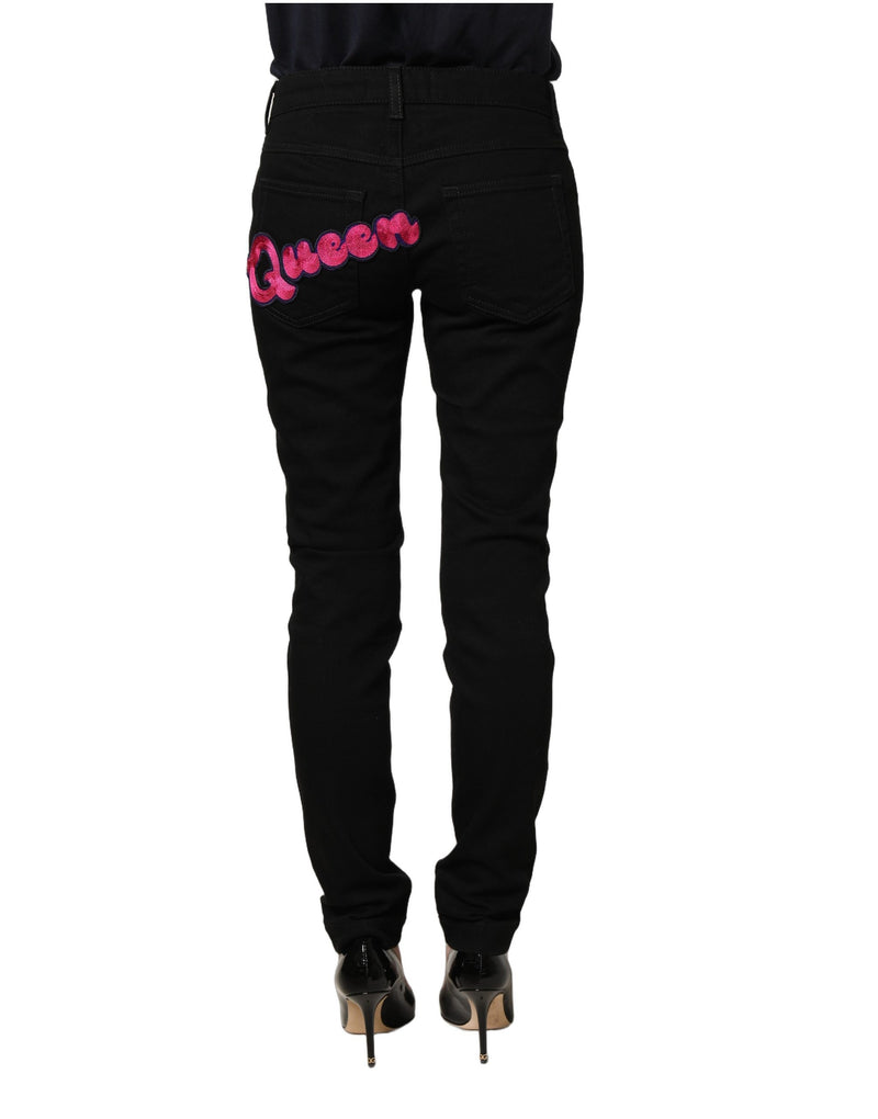 Black denim jeans featuring pink embroidered Queen lettering across the back pocket