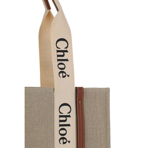 Chloé beige linen handbag featuring wide cream straps with black logo print and brown leather trim.