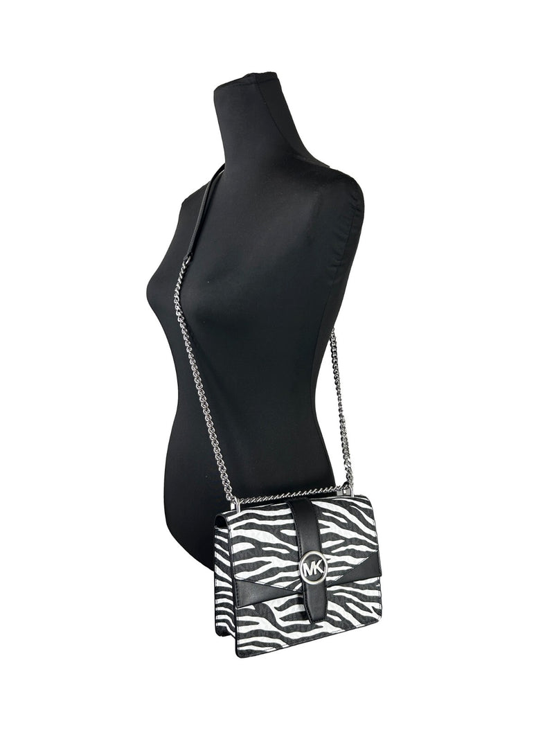Black and white zebra print leather crossbody bag with a silver chain strap on a mannequin