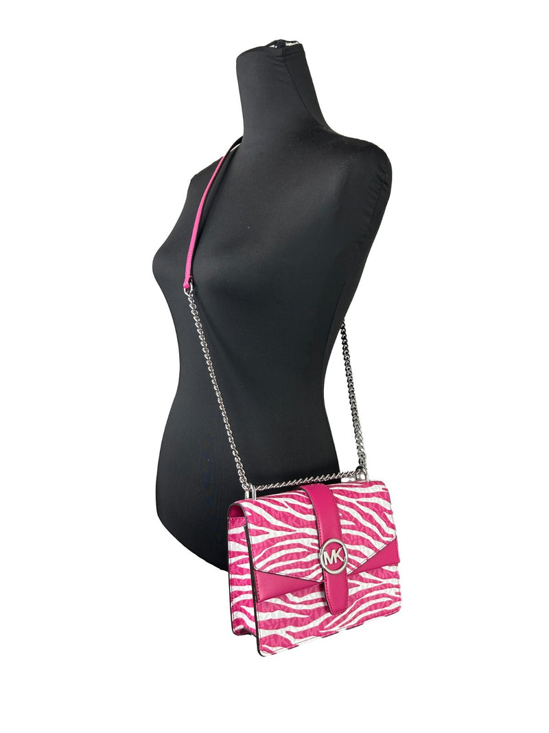 Pink and white zebra print leather flap crossbody bag with silver chain strap worn on a mannequin