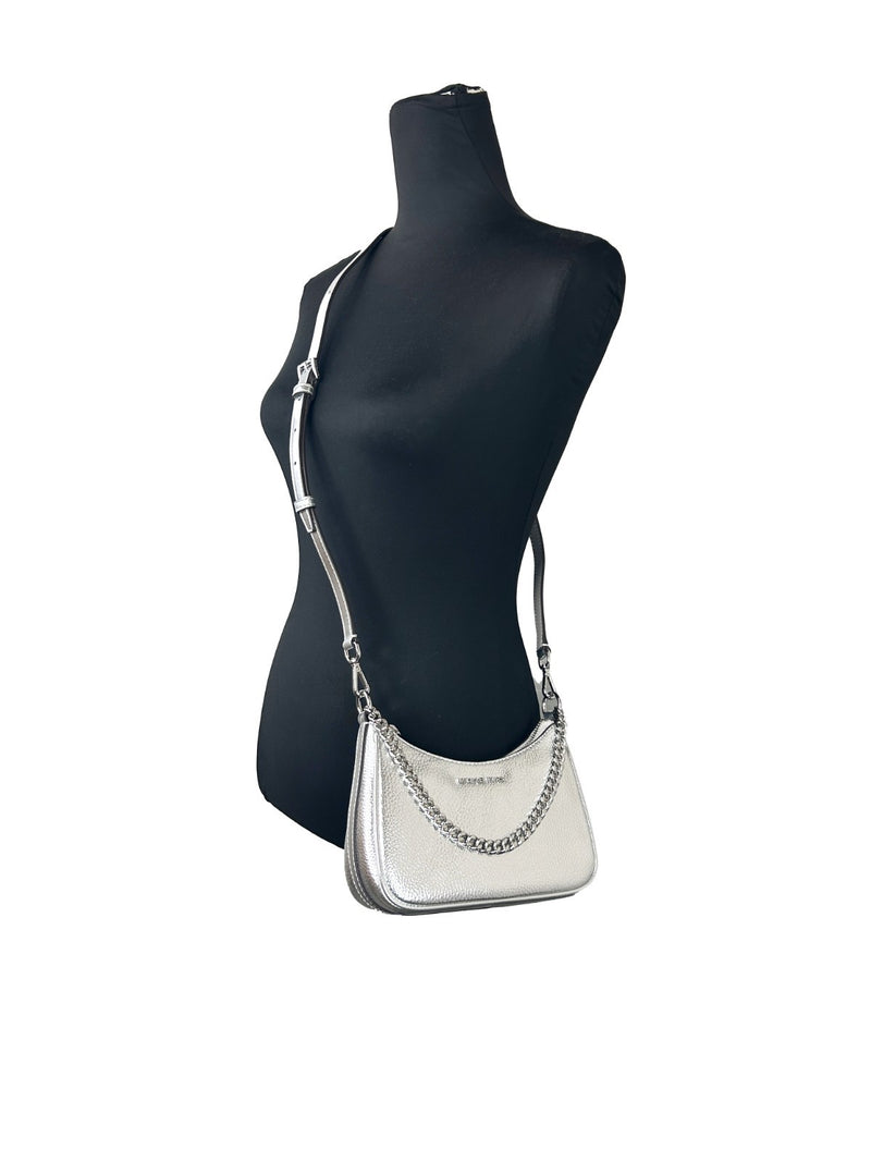 Silver leather Michael Kors small pouchette crossbody bag worn on a black mannequin