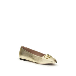 Metallic gold napa leather ballet flats with a signature gold-tone logo emblem on the rounded toe.