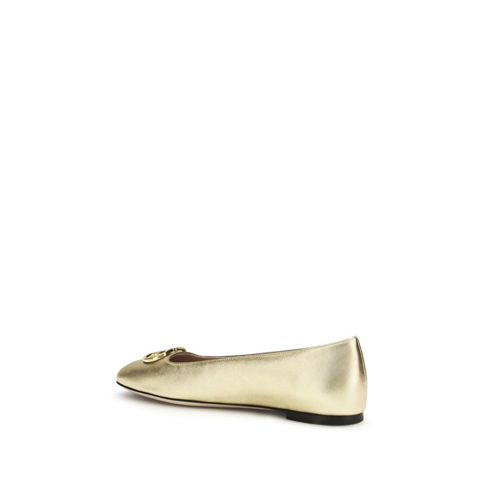 Metallic gold napa leather ballet flat by Valentino Garavani with a small gold logo accent and a flat black sole.