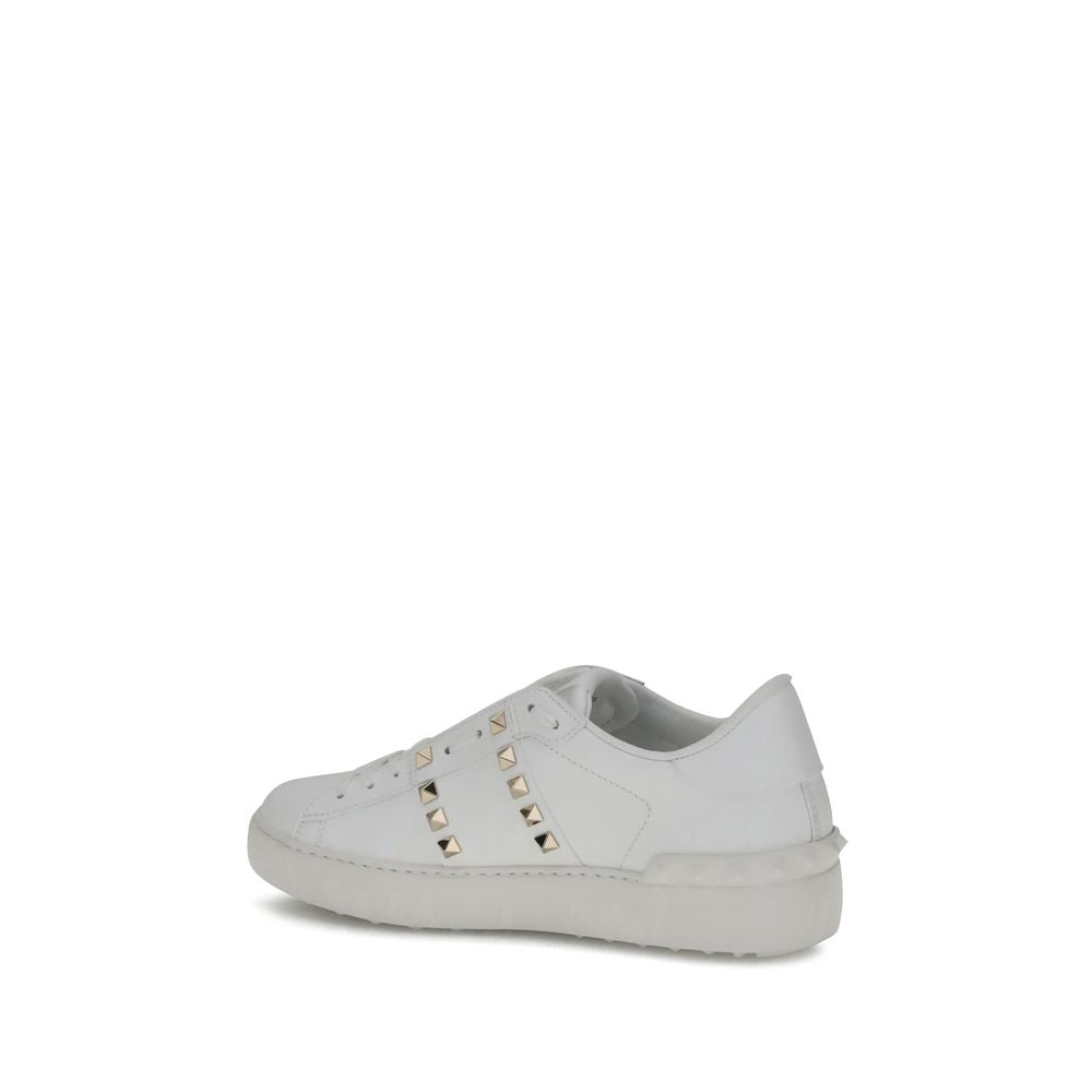 White calf leather low-top sneakers featuring gold-tone pyramid studs and a tonal rubber sole.