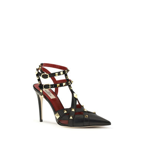 Black goatskin leather stiletto pumps with gold pyramid studs, multiple buckled straps, and a pointed toe.