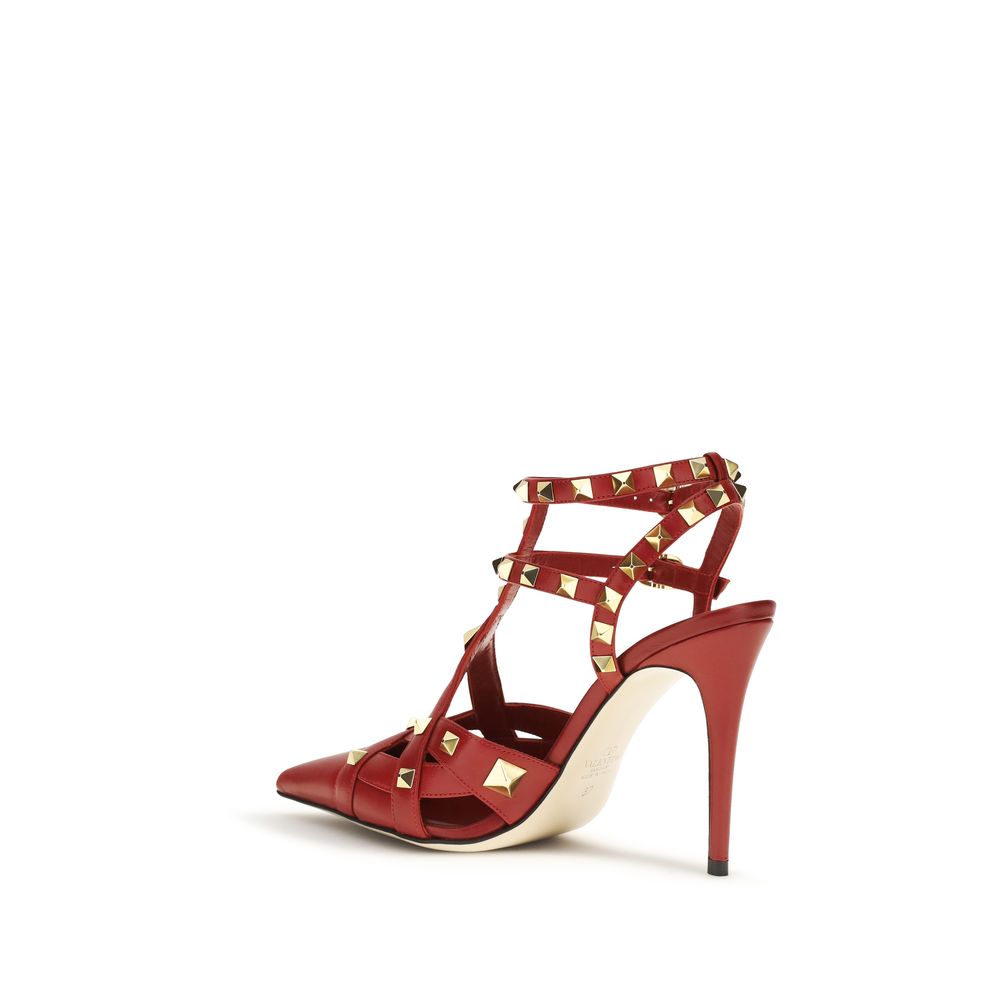 Red goatskin leather pointed-toe pumps with gold pyramid studs and strappy buckled ankle wrap.
