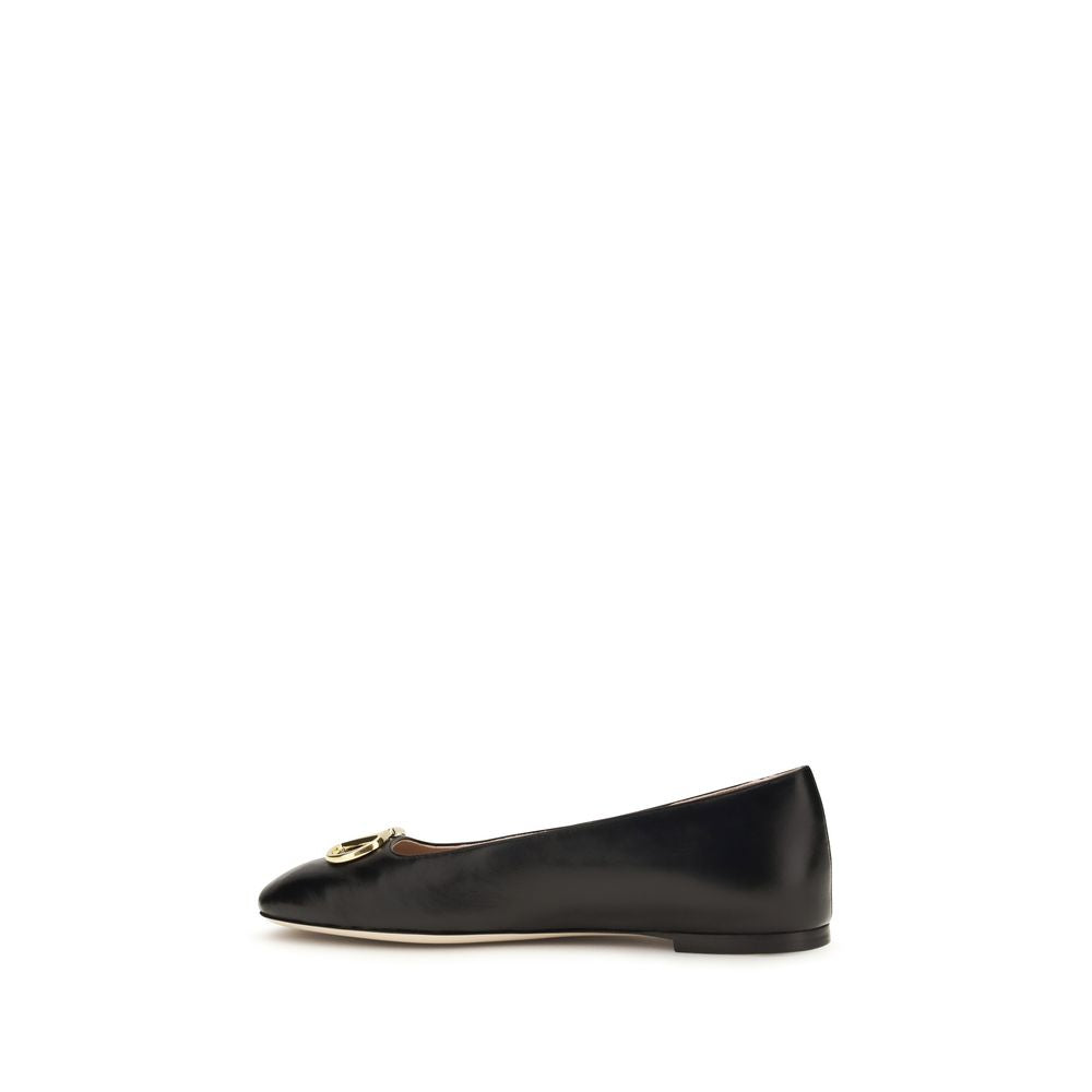 Black calf leather ballet flats featuring a gold-tone hardware logo accent on the toe.