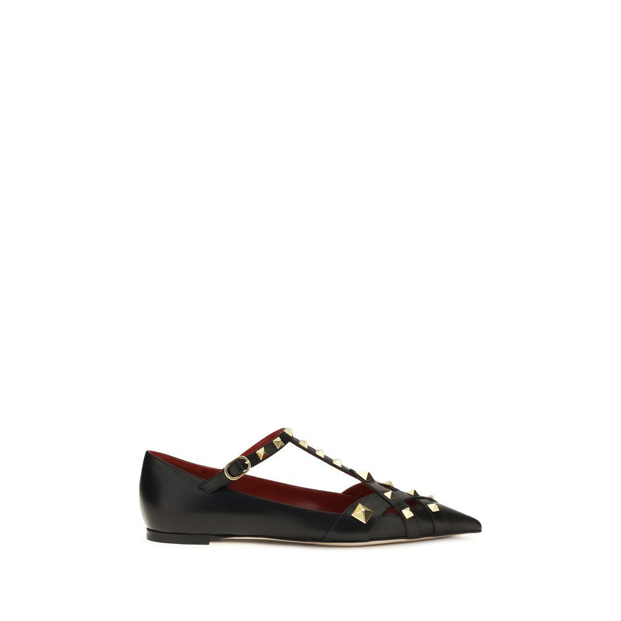 Female model wearing Valentino Garavani black goatskin ballet flats with a luxurious black goatskin upper, delicate flat silhouette, and signature Valentino Garavani detailing, captured mid-step in a casual lifestyle pose showcasing the flat's refined elegance and iconic Italian luxury craftsmanship.