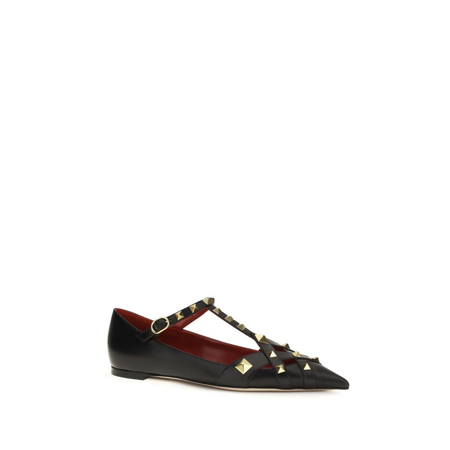 Female model wearing Valentino Garavani black goatskin ballet flats with a luxurious black goatskin upper, delicate flat silhouette, and signature Valentino Garavani detailing, captured mid-step in a casual lifestyle pose showcasing the flat's refined elegance and iconic Italian luxury craftsmanship.