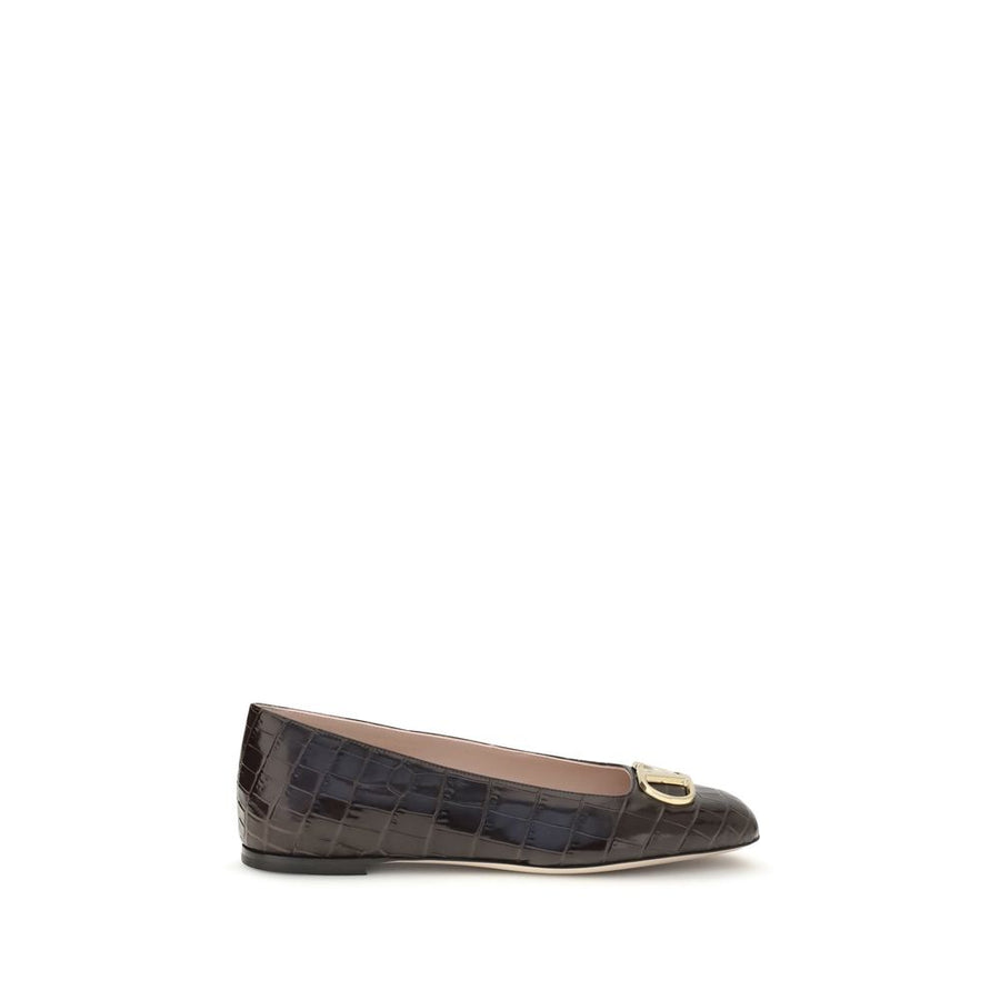 Female model wearing Valentino Garavani brown calf leather ballet flats with a rich brown calf leather upper, delicate flat silhouette, and signature Valentino Garavani detailing, captured mid-step in a casual lifestyle pose showcasing the flat's refined elegance and iconic Italian luxury craftsmanship.