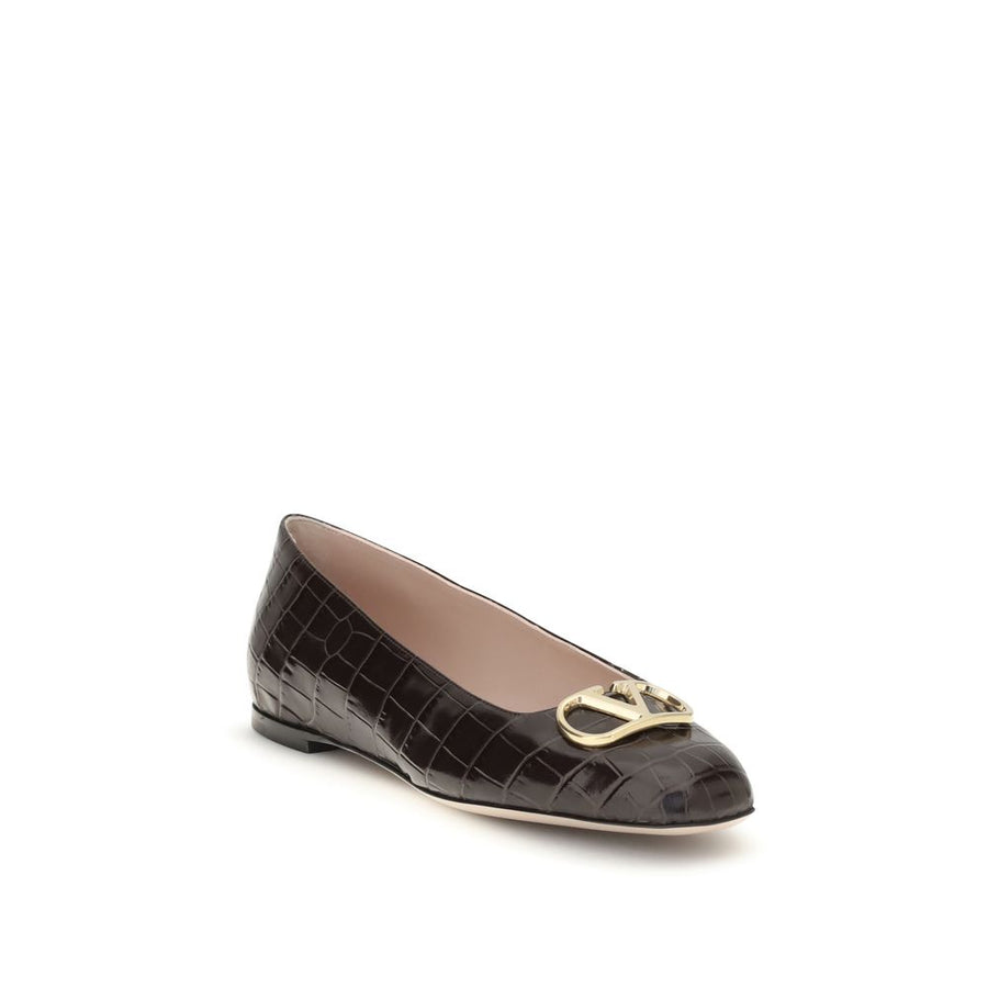 Female model wearing Valentino Garavani brown calf leather ballet flats with a rich brown calf leather upper, delicate flat silhouette, and signature Valentino Garavani detailing, captured mid-step in a casual lifestyle pose showcasing the flat's refined elegance and iconic Italian luxury craftsmanship.