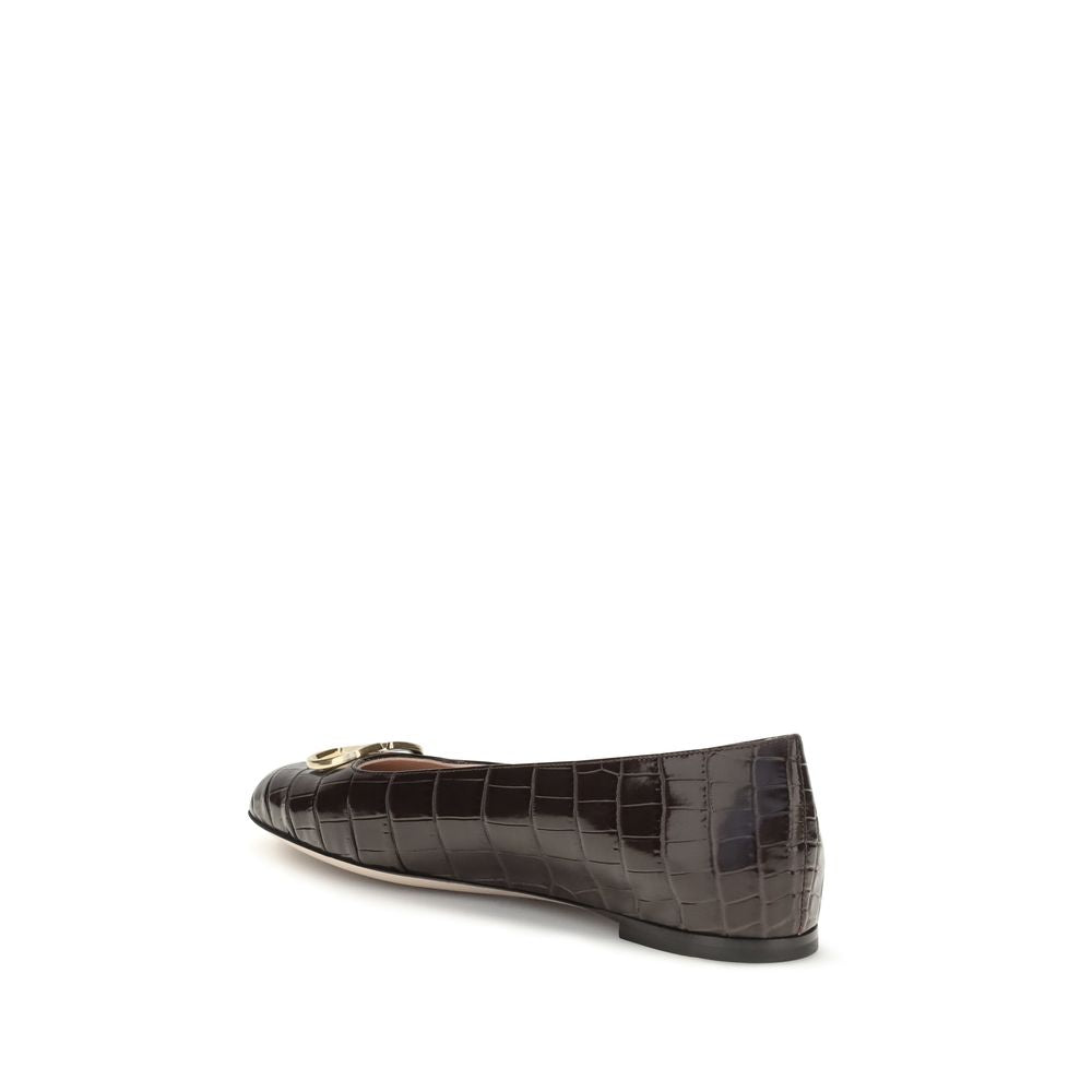 Female model wearing Valentino Garavani brown calf leather ballet flats with a rich brown calf leather upper, delicate flat silhouette, and signature Valentino Garavani detailing, captured mid-step in a casual lifestyle pose showcasing the flat's refined elegance and iconic Italian luxury craftsmanship.