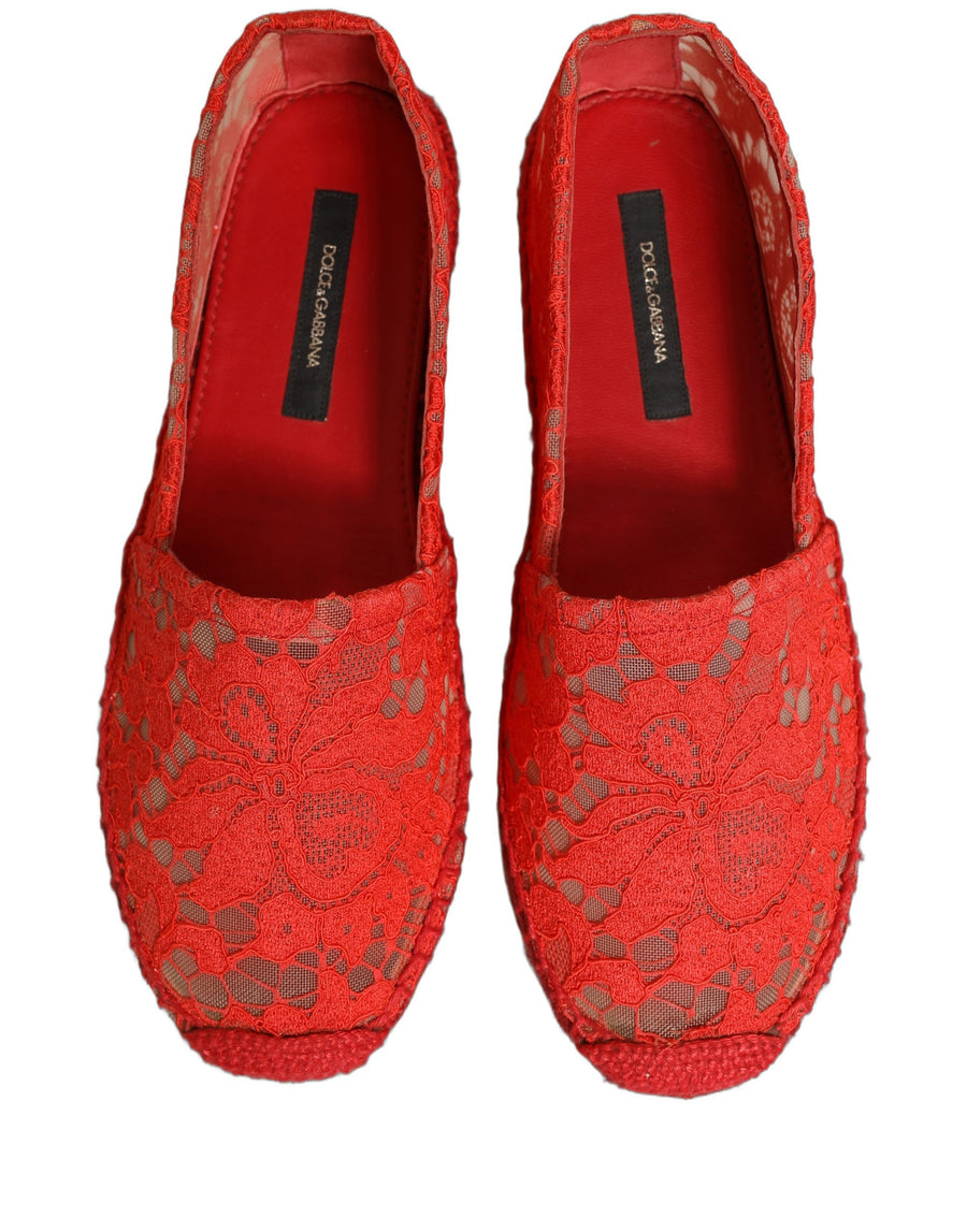 Female model wearing vibrant red floral lace espadrille slip-on shoes with a sheer lace overlay, rope-stitched espadrille sole, and bold red colourway, captured mid-step in a casual lifestyle pose showcasing the shoe's elegant profile and delicate lace detailing.